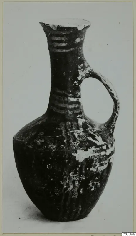 Jug with a single loop handle and banded neck, dark surface with pale patches of wear.