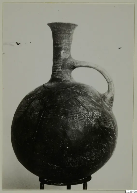 Round-bodied jug with a tall flaring neck and single loop handle, with incised dashes on neck and shoulder, shown on a metal ring stand