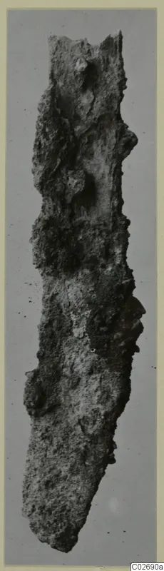 Heavily corroded iron knife blade, shown upright.