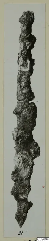 Corroded metal tool from Marion, long and narrow, tapering to a point at the lower end