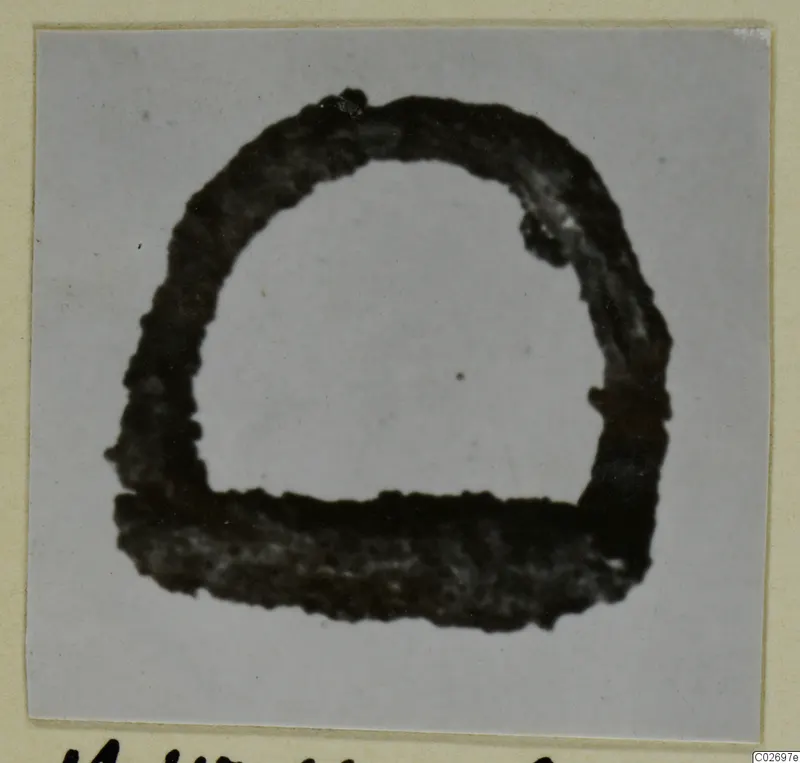 Corroded iron tool, semicircular with a flat base, shown close up on a mounted photograph card.