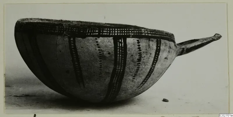 Bowl with a long handle to the right, decorated with dark painted bands and cross-hatching, photographed in side view