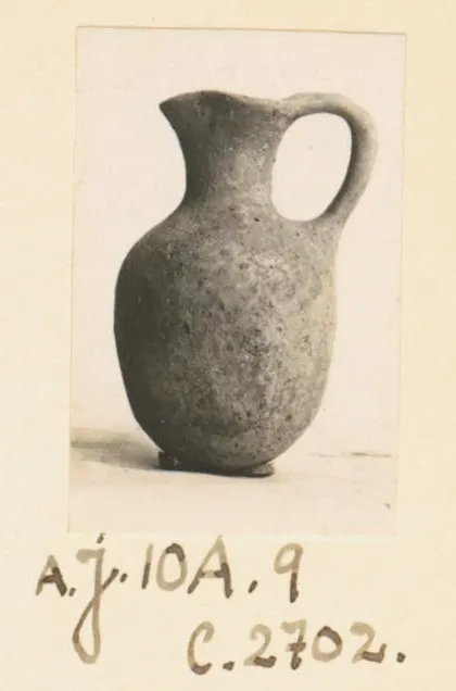Juglet with a rounded body and single loop handle, photographed on an album page from Ayios Iakovos