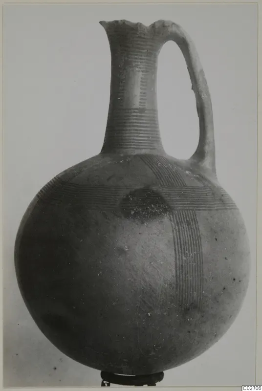Jug of Red-on-Black etc pottery with a tall neck, single loop handle and bands of fine lines