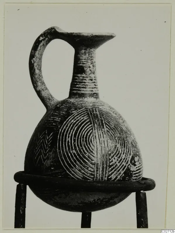 Pottery Red Polished II jug with a single loop handle and incised concentric circles and chevron bands on its body.