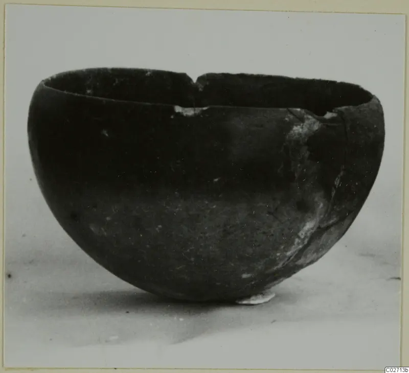 Red Polished II bowl, a dark rounded bowl with a broken rim photographed on a pale surface.