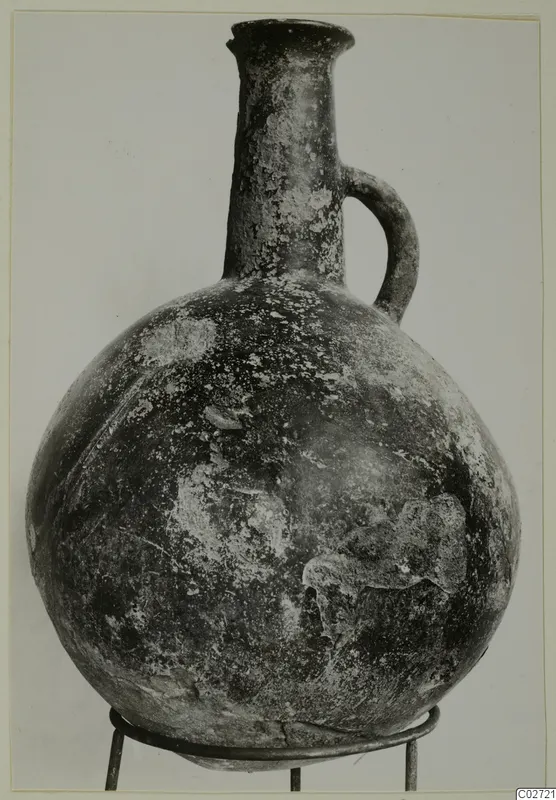 Round-bodied jug with a tall neck and single loop handle, standing on a wire stand against a plain background.