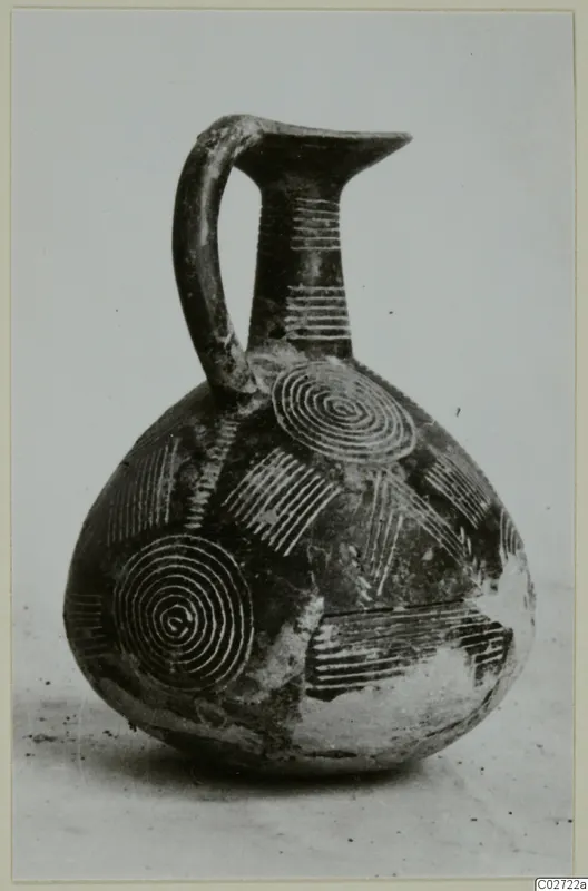 Pottery Red Polished II jug with a high strap handle and concentric circle decoration