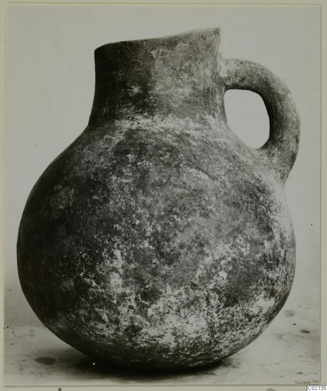 Jug with a rounded body, tall neck and strap handle, photographed against a plain background