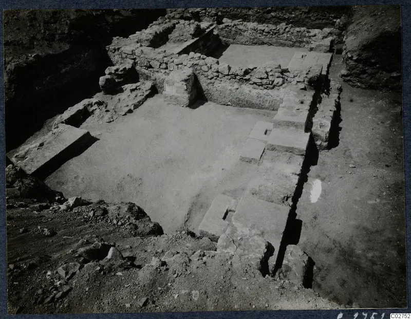 Excavated stone structure at Soli, with low rubble walls, a paved floor and stone blocks in a trench