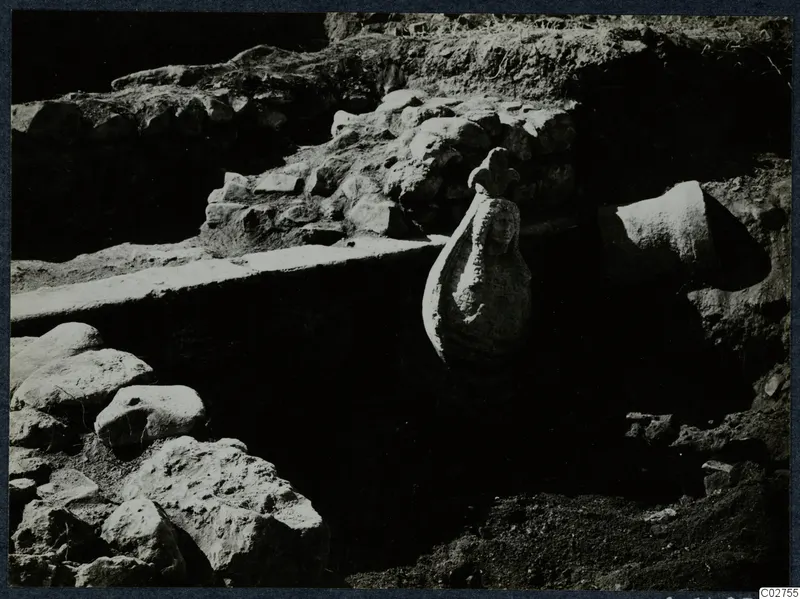 Carved stone figure standing in an excavated trench among wall remains at Cholades, Soli.