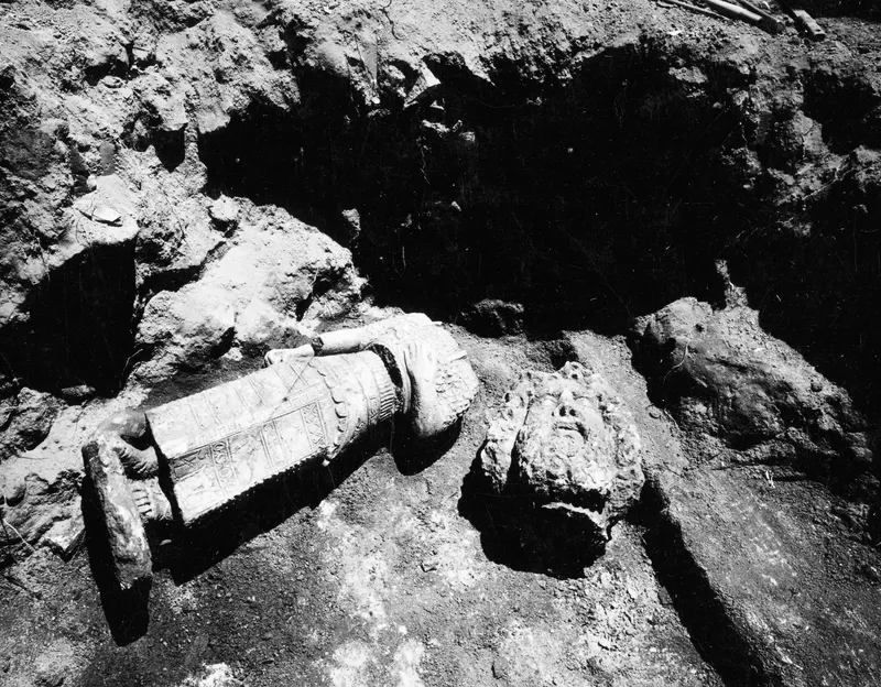Carved stone sculpture fragments lying in situ in Room XXXIV at Soli, with a head to the right of a long patterned piece.