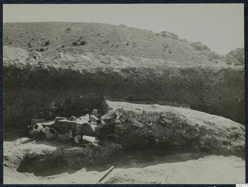 Excavated trench at Mersinaki with pottery vessels and sherds on the left beside a large stone block