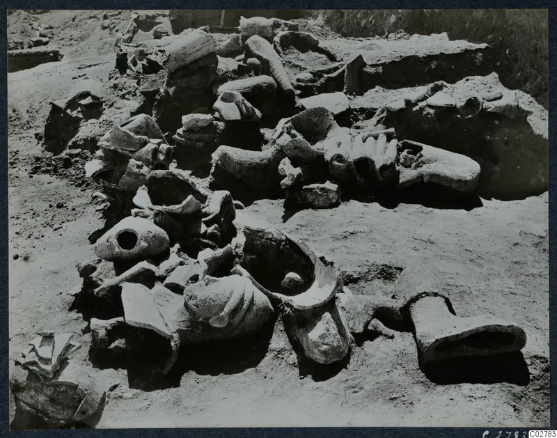 Statue fragments, including heads and a foot, lying together in an excavated area at Mersinaki