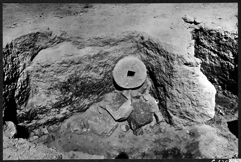 Excavation at Mersinaki: a round stone disc with a square hole set against an earth face in a cutting