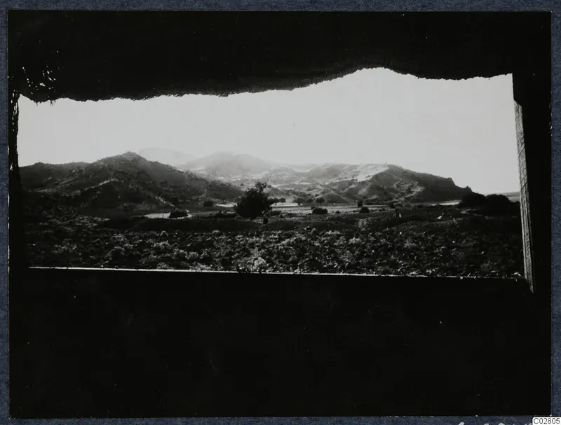 View through a tent opening over fields and hills toward Vouni at Mersinaki