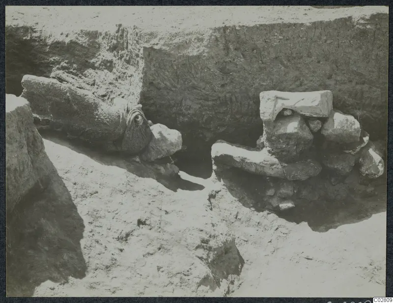 Stone objects lying in situ in a trench at Mersinaki, Pit II, with an earth section behind them