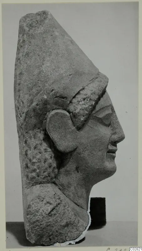 Limestone sculpture head from Kition, shown in profile facing right, with a tall headdress and carved hair.