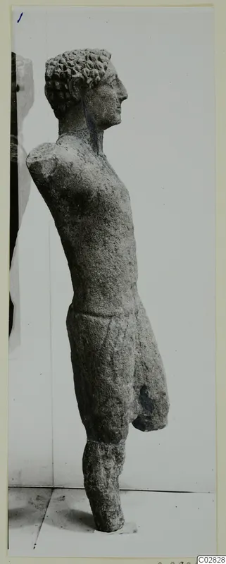 Limestone statue of a standing figure in profile, facing right, with arms and lower legs broken off