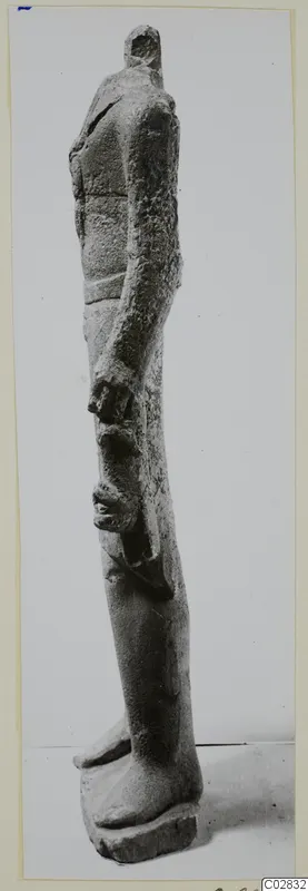 Limestone statue of a standing figure seen in profile, head broken off at the top