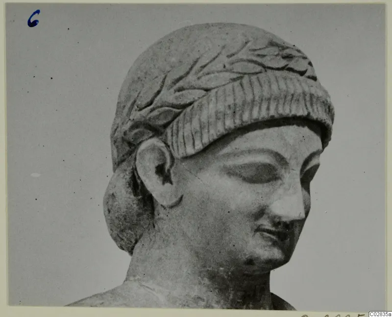 Limestone head and upper shoulders of a statue, with a leaf-carved band over the hair and eyes lowered, from Kition