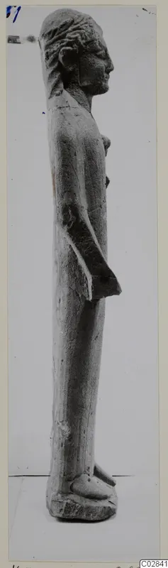 Limestone statue of a standing figure, seen in profile facing right.