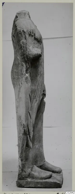 Side view of a headless limestone statue of a standing figure from Kition, on a rectangular base