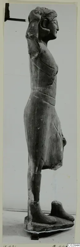 Limestone statue of a standing figure from Kition, seen in profile with one arm raised to the head