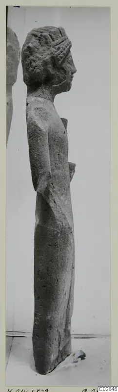 Limestone statue of a standing figure seen in profile, facing right