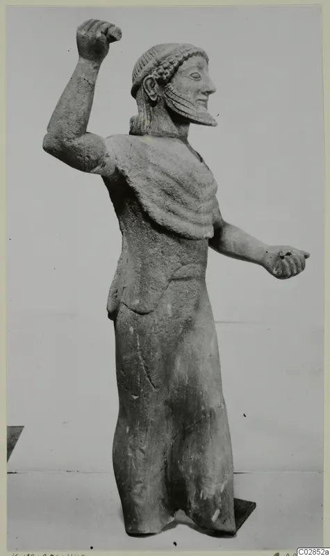 Limestone statue of a bearded standing male figure from Kition, one arm raised with a clenched fist