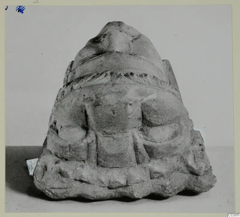 Carved stone sculpture fragment from Kition, with a rounded top, a twisted banded moulding and relief details