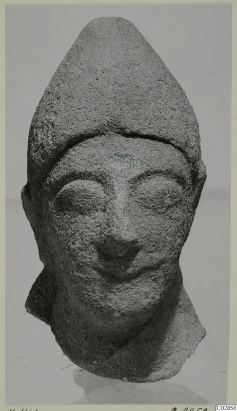 Limestone head statue fragment from Kition with a tall pointed headdress and a slight smile