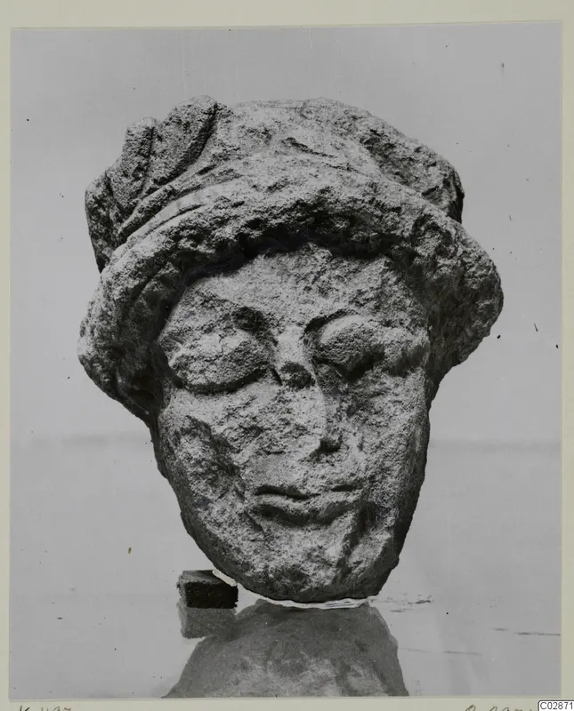 Limestone head of a statuette from Kition, wearing a close-fitting cap, with a worn and damaged face
