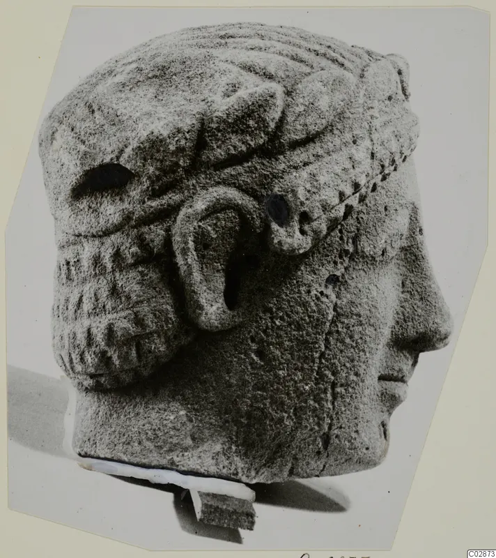 Limestone head in right profile, wearing a wide band with ridged decoration, set on a small stone base.