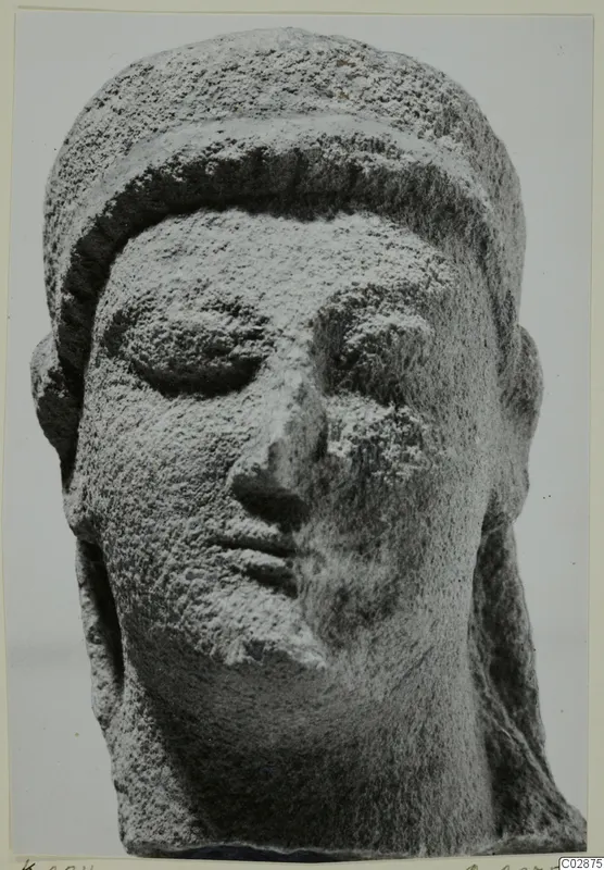 Limestone head of a sculpted figure with downcast eyes and a wide band over the hair, its surface worn.