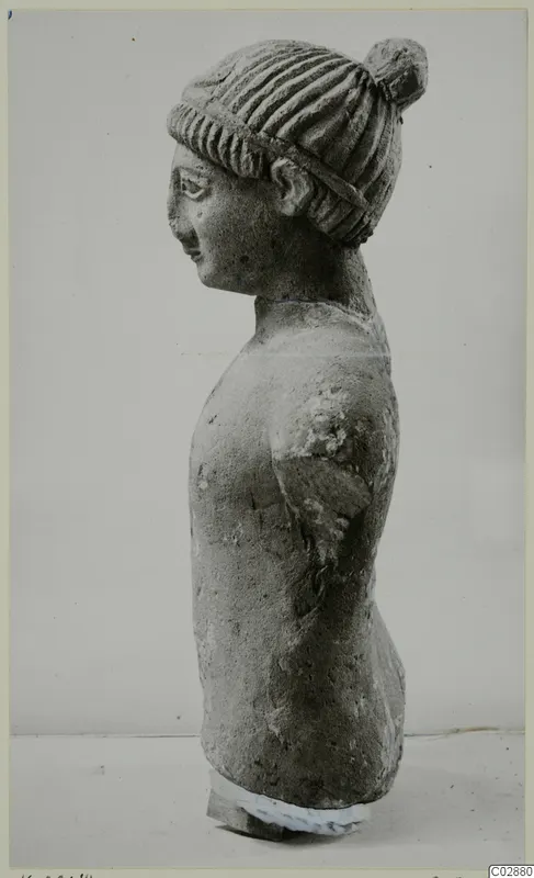 Limestone statue of a head and upper torso in profile, hair in a bun with a band, from Kition