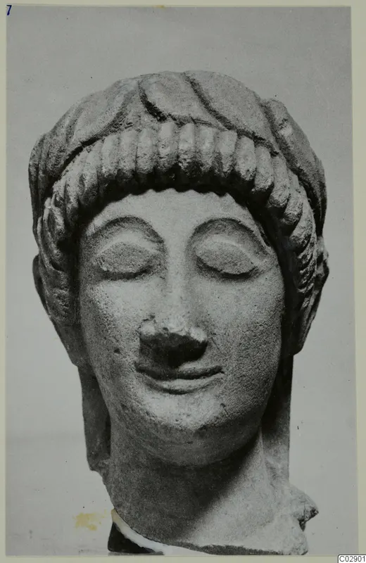 Limestone head of a statue with closed eyes and hair in rows of curls over the forehead
