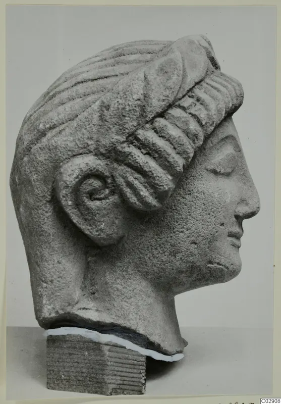 Limestone head from Kition, shown in profile facing right, with ridged wavy hair and a carved ear.