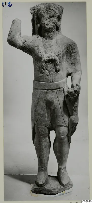 Limestone standing statue of a figure with a worn head, one arm raised and a belted short garment, on a rough base