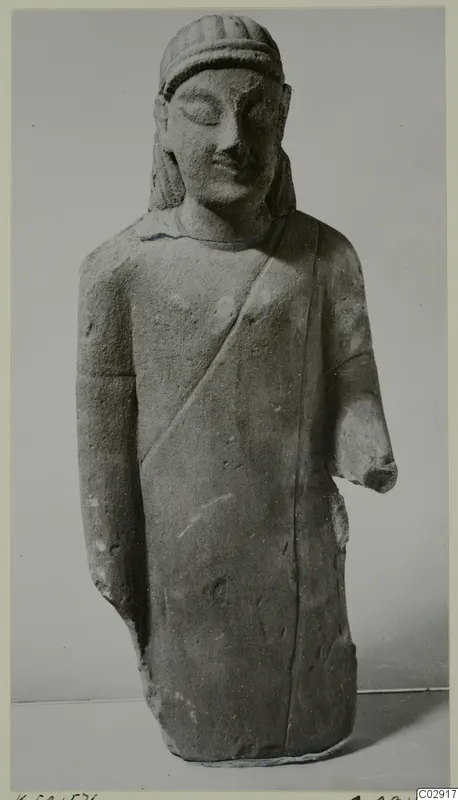 Limestone statue of a standing male figure from Kition, with a cloak across the chest and a broken right forearm