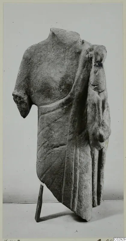 Limestone sculpture fragment of a draped torso with a smaller figure carved at its right side