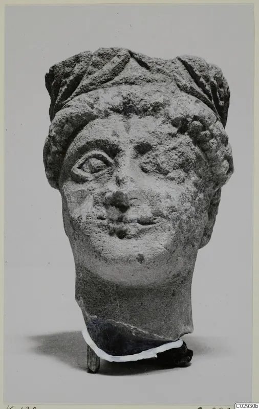 Limestone head fragment from Kition, front view against a plain grey background