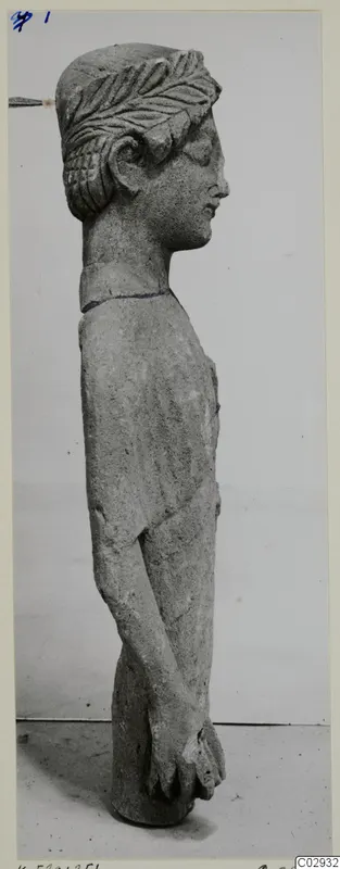 Limestone statue of a standing figure seen in profile, with carved hair and hands clasped at the front of the body