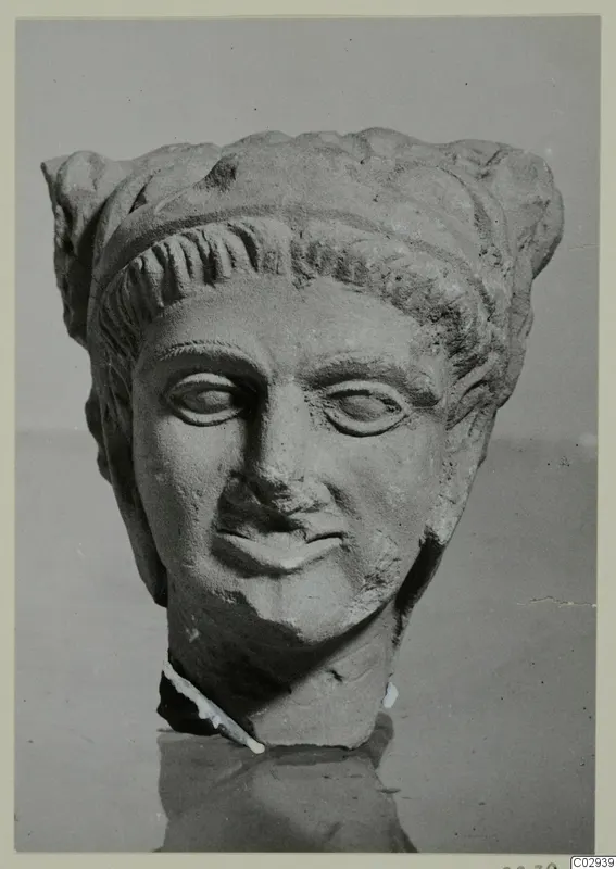 Sculpted stone head of a figure in a high headdress with curled locks over the brow, neck broken off, Kition