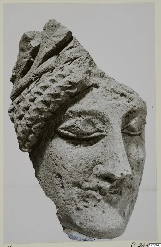 Limestone head fragment from Kition with almond-shaped eyes, a straight nose and a ridged headdress