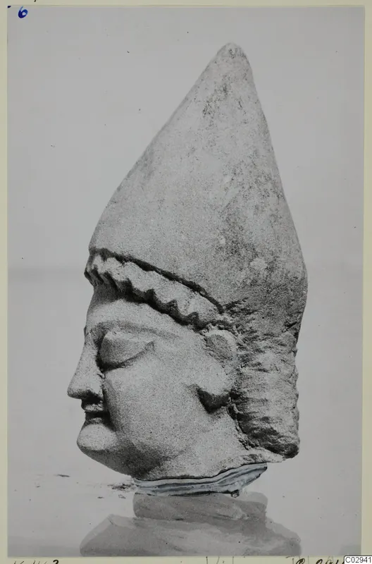 Limestone head statue from Kition in profile, with a tall pointed headdress and a zigzag ridged band across the brow.