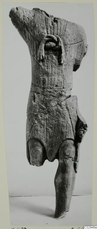 Limestone statuette fragment of a standing figure, head and upper body broken away, shown upright against a plain backdrop.