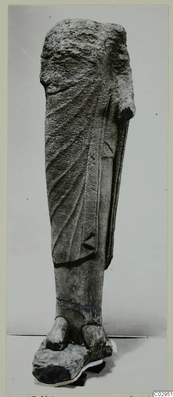 Limestone statue fragment from Kition: draped lower body and feet, with the head and right arm broken away.