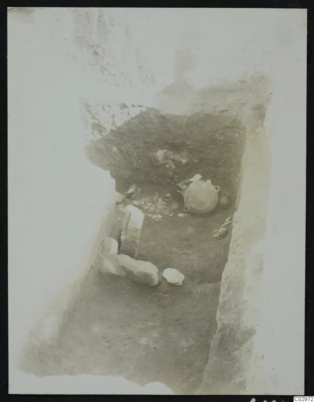 Excavation at Amathus with a round two-handled vessel, a small jug and stone slabs in a cut trench