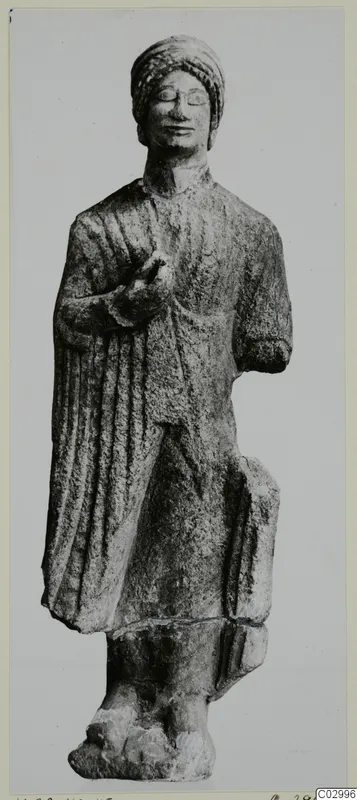 Limestone standing figure from Vouni with a wrapped headdress and right hand raised to the chest.